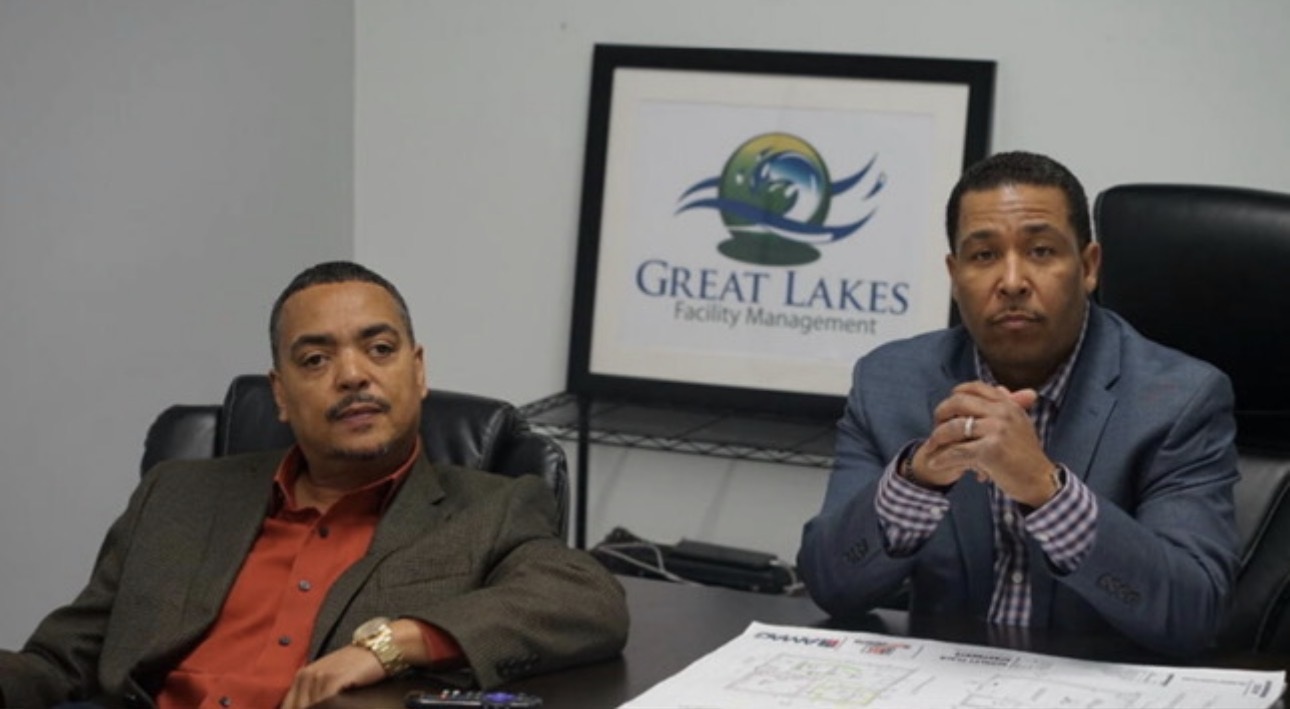Great Lakes leadership seated in the company office beside the Great Lakes Facility Management logo